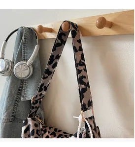 Detail of leopard print canvas bag with wide strap hanging with denim jacket