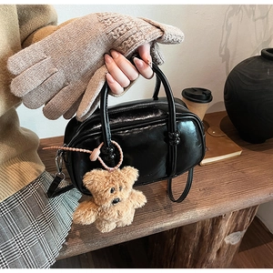 Detail of a shiny black bowling bag with a cute plush bear pendant in an autumn setting