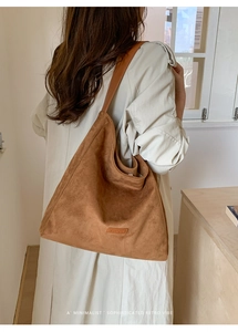 Detail of brown faux suede tote bag featuring a leather brand tag and soft shoulder strap