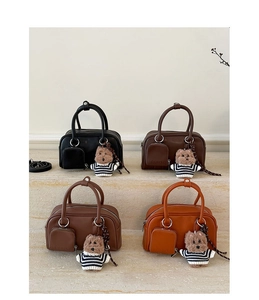 Four retro Boston handbags in varied colors with bear charms on marble steps