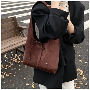 Détail d'un sac cabas en daim marron avec nœud à cordon et pendentif cœur argenté chic