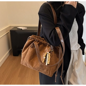 Detail of vintage brown suede shoulder bag with drawstring closure and wooden bead charm