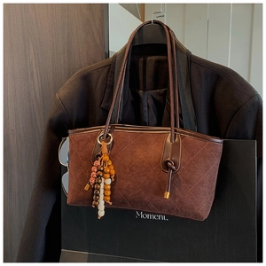 Detail of dark brown quilted suede tote bag with colorful beaded charm and handle