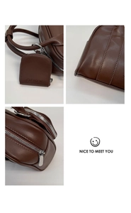 Detail of dark brown leather handbag with silver zipper and mini square charm pouch