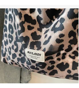Close-up of leopard print crossbody bag featuring a white stitched leather brand label