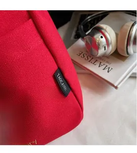Close-up of red canvas bucket bag showing detailed black woven label and white embroidery