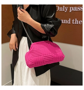 Detalle de bolso acolchado rosa fucsia con cadena llevado por modelo con chaqueta de cuero