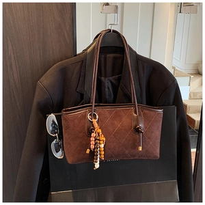 Detail of dark brown quilted suede tote bag with colorful bead tassel and thin leather strap