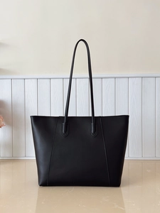 Close-up of minimalist black tote bag with slender leather straps and fine texture