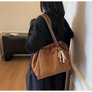 Detail view of large brown suede hobo bag featuring ethnic beaded charm and drawstring closure