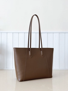 Detail view of large dark brown leather tote bag with fine stitching and slim shoulder straps