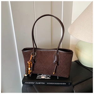 Detail of vintage brown quilted tote bag with suede texture and beaded fringe tassel decor