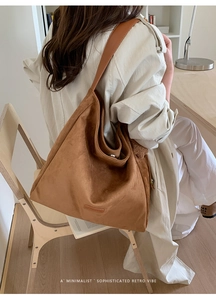 Side view of large brown suede tote bag worn by model in a minimalist retro setting