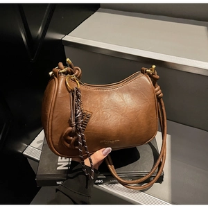 Detailed macro of vintage brown leather crescent bag with gold zipper and knotted strap