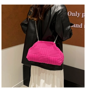 Detail of bright pink woven clutch with silver chain strap on a fashion model