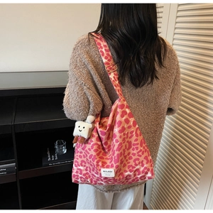 Detail of pink leopard print shoulder bag with adjustable wide strap and plush toast charm