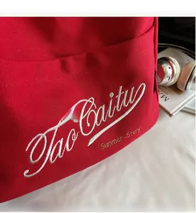 Close-up of red canvas tote bag with white embroidery and summer story print