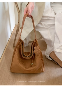 Close-up of brown suede hobo bag with teddy bear pendant and shoulder strap detail