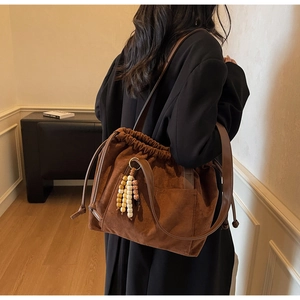 Detailed view of brown suede bucket bag with colorful wood bead tassel and drawstring