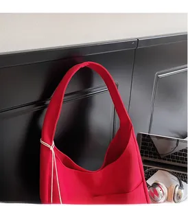 Detail of red canvas tote bag featuring wide handles and white cord wrapping decor