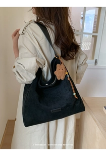 Close-up of black suede tote bag with cute plush bear pendant and beaded charm detail