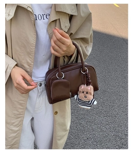 Close-up of vintage brown leather handbag with mini pouch and cute teddy bear charm