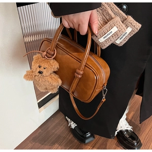 Detailed shot of brown leather bowling bag with a cute plush bear charm accessory
