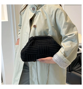 Detalle de bolso nube negro plisado con cadena metálica sobre una gabardina color beige
