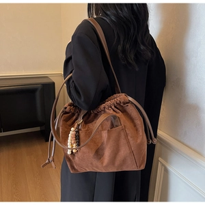 Detail of brown suede drawstring bucket bag with bohemian tassel and beaded charms