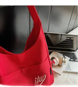 Detail of red canvas bucket bag with white embroidery embroidery and dense texture