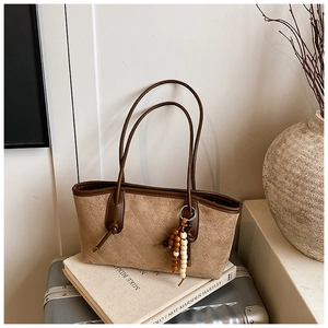 Detailed view of brown quilted tote bag with wooden bead charm on elegant art books