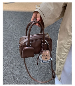 Detail of vintage brown leather handbag with a small coin purse and plush puppy charm