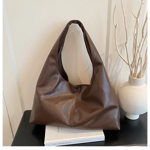 Detail of a large dark brown faux leather tote bag in a minimalist hobo style setting