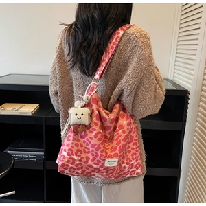 Detail of pink leopard print canvas tote bag with plush bread charm and logo label