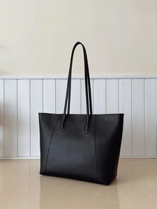 Detail of V-shaped stitching and matte leather texture on a large black tote bag