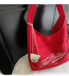 Close-up of red canvas tote bag featuring white embroidery and a mini coin purse charm