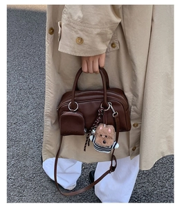 Detail of vintage dark brown leather bag with mini pouch and dog charm in street style