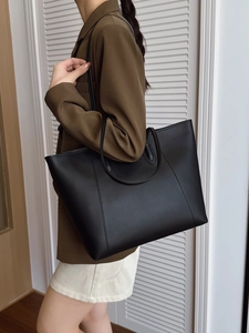 Side view of a large black minimalist tote bag on model for professional commuting