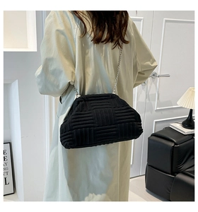 Détail d'un sac coquillage tissé noir avec chaîne argentée porté par un mannequin