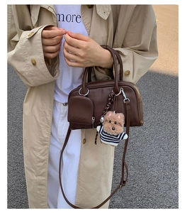 Detail of dark brown boston bag with a small pouch and plush dog charm in street style