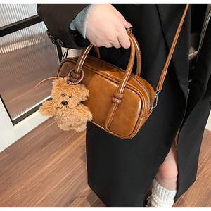 Brown vintage leather bowling bag with teddy bear charm shown in a lifestyle pose