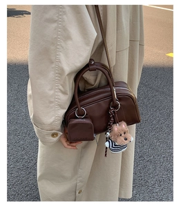 Detail of dark brown leather Boston bag with plush dog charm and side coin purse accessory