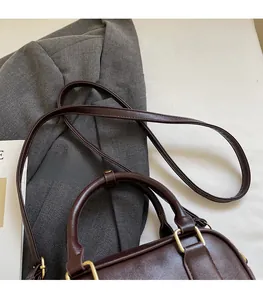 Detail view of adjustable strap with gold-tone hardware on dark brown crossbody bag