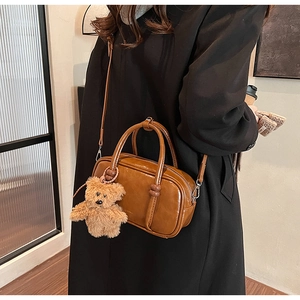 Brown leather bowling bag featuring a cute plush bear pendant and detachable strap