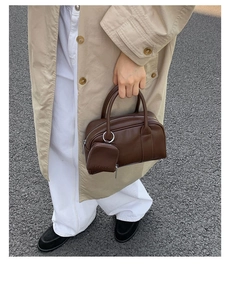 Detail view of dark brown leather handbag with a detachable mini zipper pouch on street background
