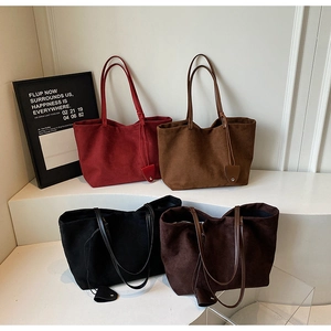 Detail view of large faux suede tote bags in various vintage colors with leaf charms