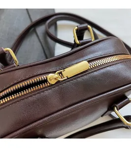 Detail of smooth gold alloy zipper and neat stitching on dark brown leather handbag