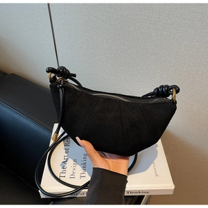 Dettaglio borsa a mezzaluna in camoscio nero con cuciture 3D e accenti a tracolla annodati