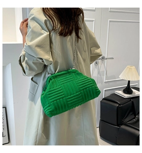 Détail du sac coquille tressé vert avec textures géométriques et chaîne argentée sur mannequin