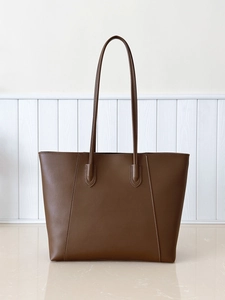 Detail view of large brown leather tote bag with vertical reinforced stitching and handles